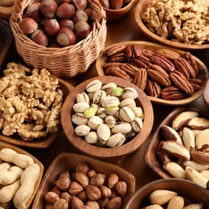 Assorted nuts displayed in wooden bowls including pistachios, pecans, walnuts, hazelnuts, and peanuts