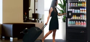 Traveler using a smart cooler vending machine with digital touchscreen to purchase drinks and snacks.